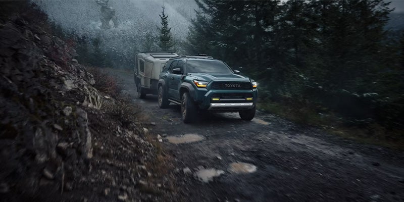 A Toyota 4Runner driving down a mountain on a dirt road with a trailer hitched behind it.